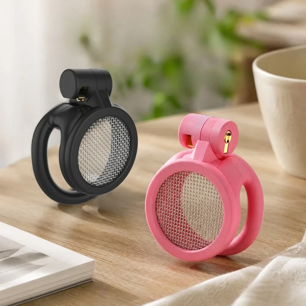 Cintos de castidade masculino micro preto e rosa lado a lado sobre mesa de madeira