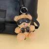 Ursinho BDSM com arnês em X preso no zíper de uma mochila preta
